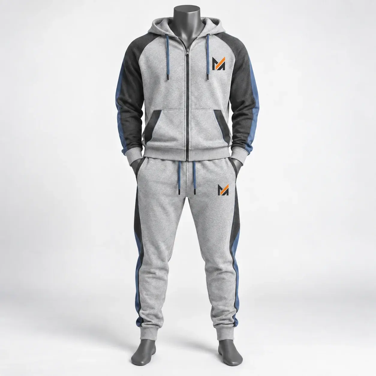 Light gray fleece and French terry tracksuit with charcoal sleeves, blue side accents, hooded zip jacket, tapered joggers, and Mega Apparel logo on the chest and pants.